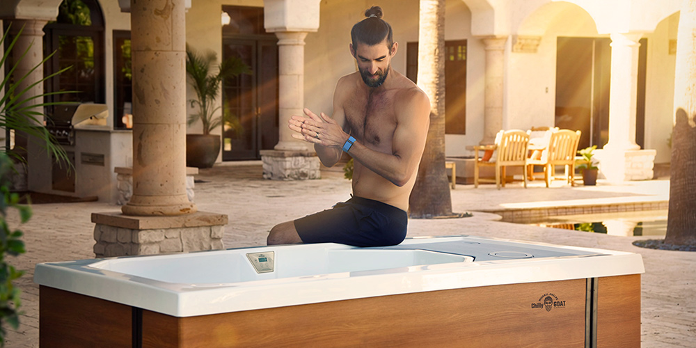 Michael Phelps sitting on the edge of a cold tub rubbing his hands together.