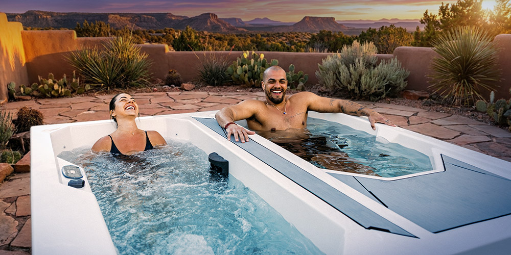 Woman in the hot tub side and a man in the cold side of a Valaris Chilly GOAT Cold Tub.