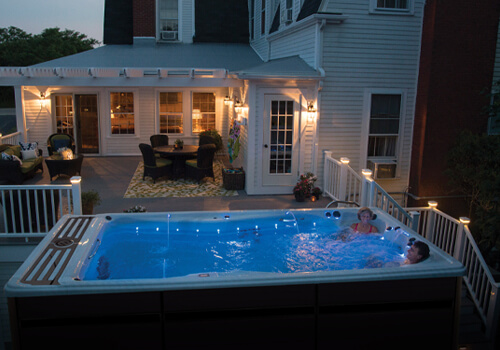 A nighttime view of a swim spa with led lights turned on