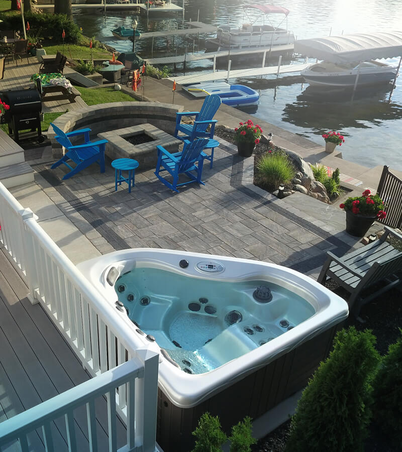 Ultimate Lake House. This patio features built-in fire pit, colorful seating, planters, and two-person hot tub.