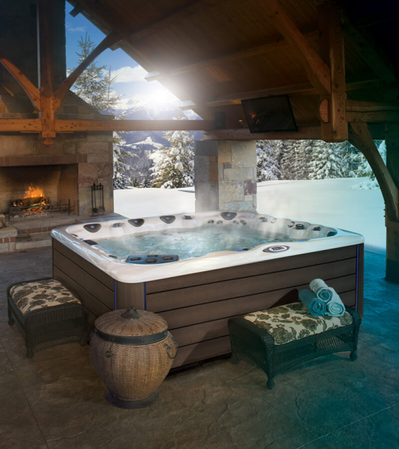 Hot Tub in Winter. A large outdoor fireplace and open-air structure create a cozy space to relax.