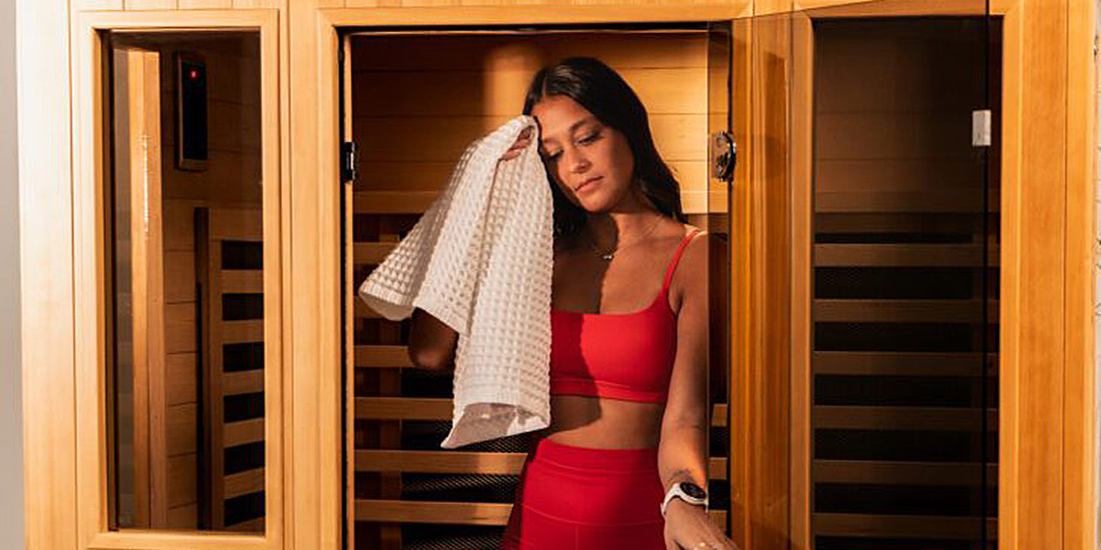 Woman wiping sweat from her forehead leaving a sauna.